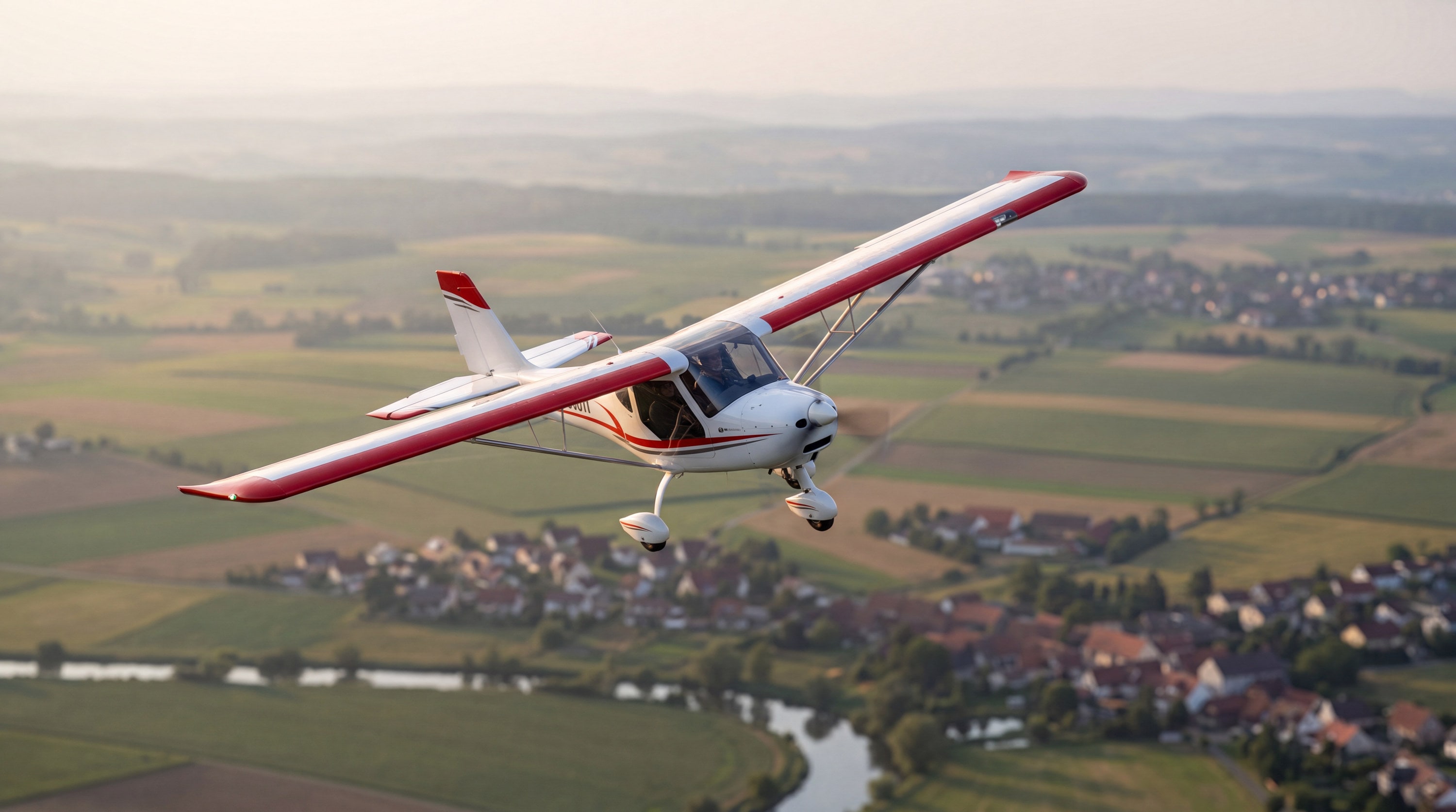 Weiß-rotes Ultraleichtflugzeug im Abendlicht über deutschen Feldern, zwei Menschen im Cockpit